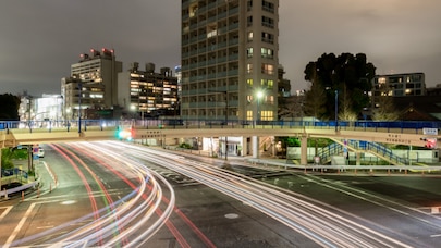 Cars leave light trails as they travel along a city road at night