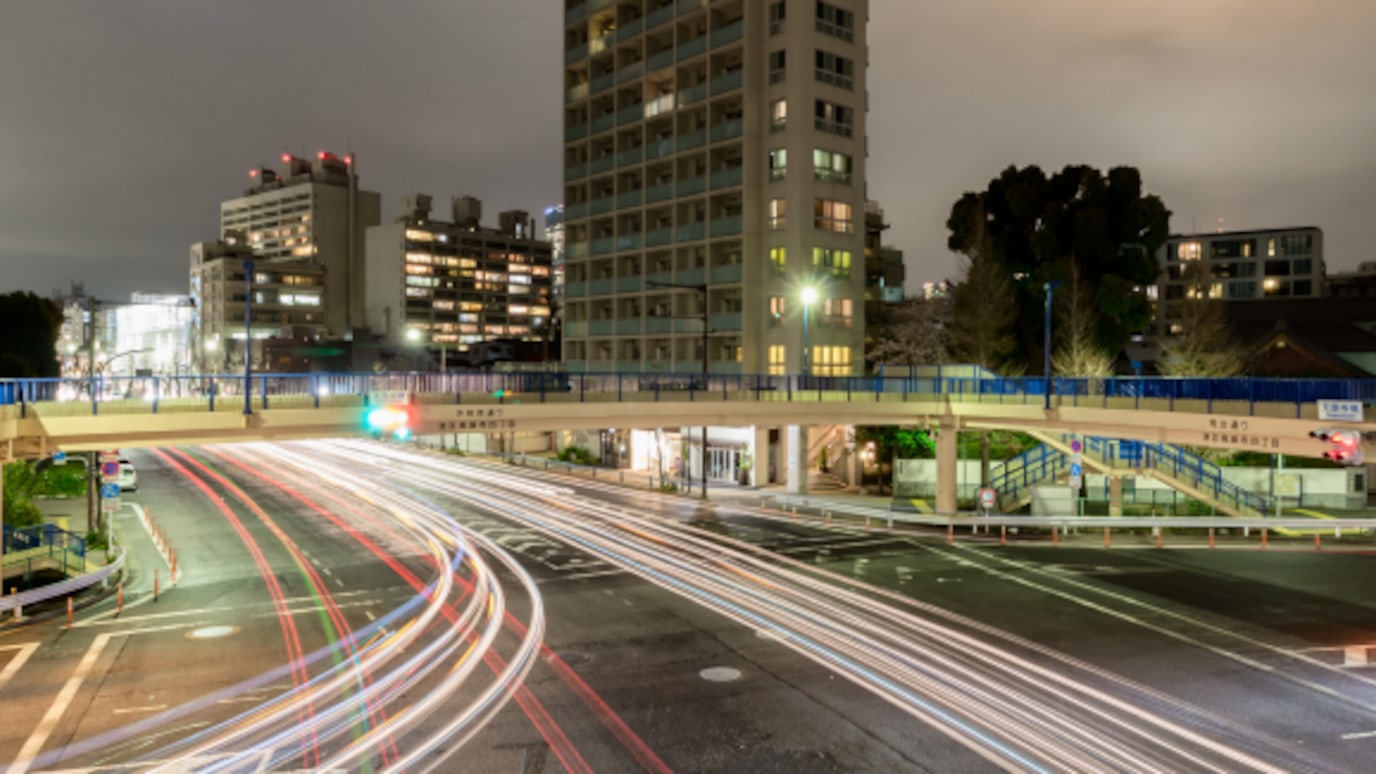 Cars leave light trails as they travel along a city road at night