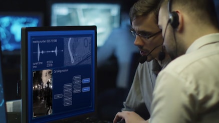 Men with headsets in situation room look at monitor screen