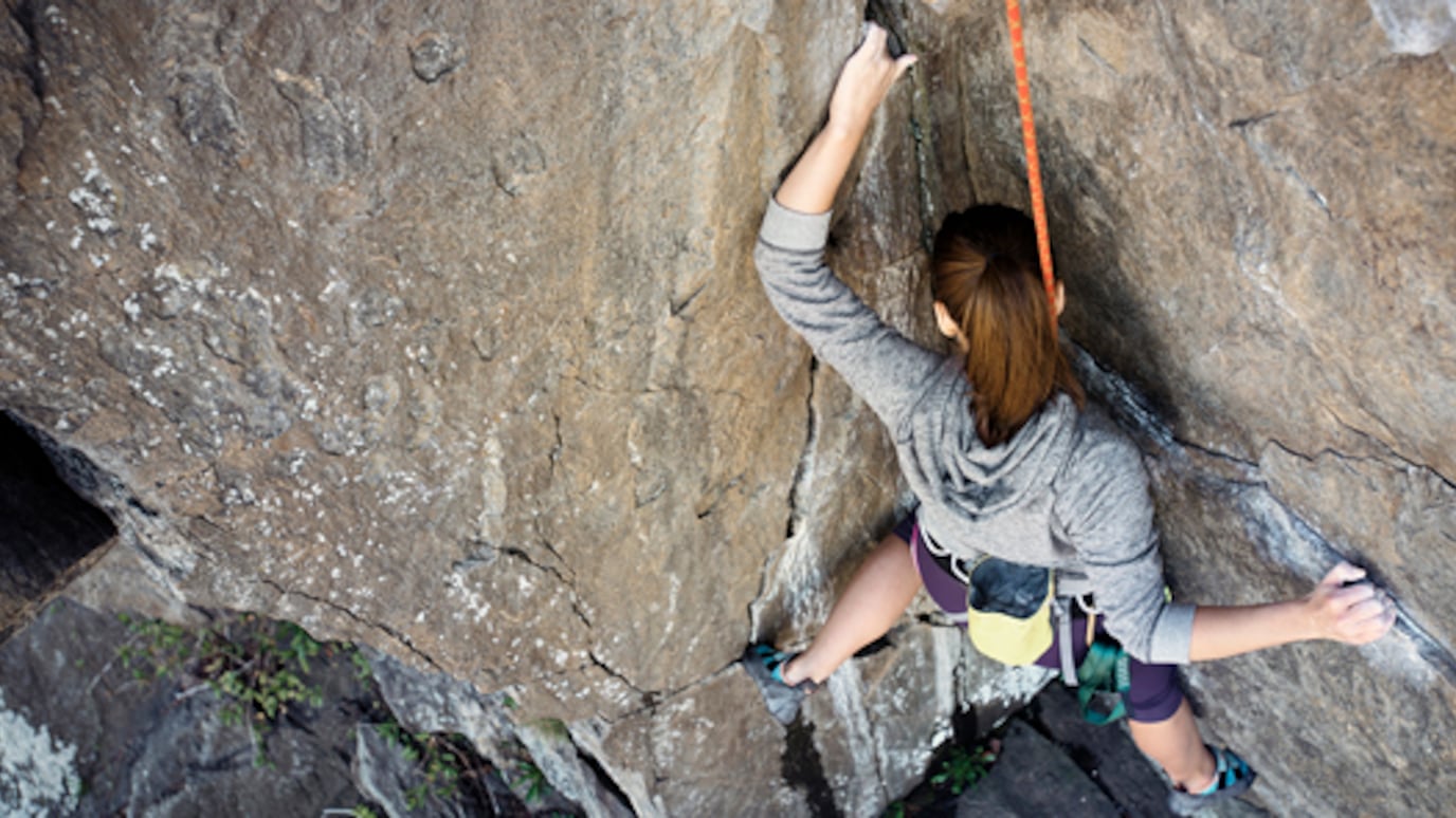 A woman climbing a steep cliff face.