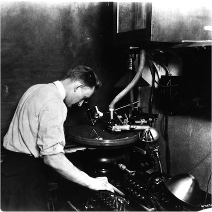 Close-up view of recording turntable. Attendant views the record-cut through a microscope