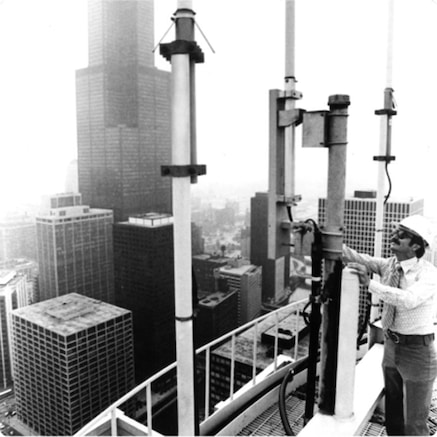 Man examining cellular aerials on a building roof in a city