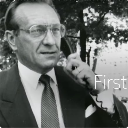 Black and white photograph of man in suit making a GSM call