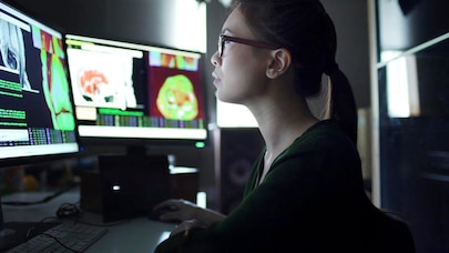 Woman sat at desk in front of two computer monitors