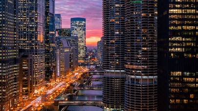 An image of a river with high-rise buildings on both sides of it and a sunset in the background.
