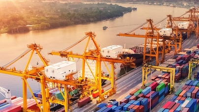 A picture of harbour cranes and containers by a river