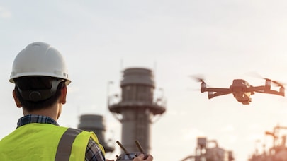 A picture of a worker in safety gear flying a drone.