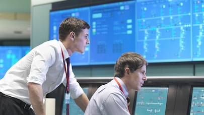 Two people working and looking at the same computer screen.