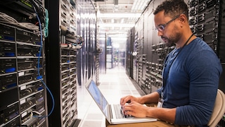 Engineer working on laptop connected to servers