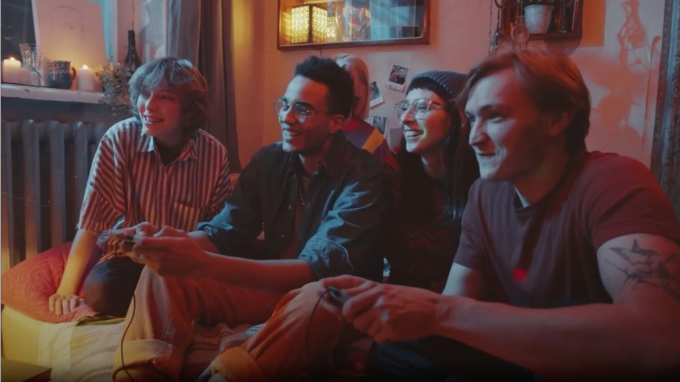 Teenagers sat in a row holding gaming console remote controls