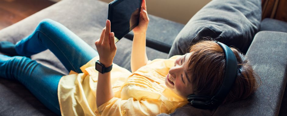 A woman enjoying music while gazing at a tablet.