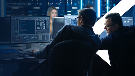 Two people looking at the same computer screen, working.