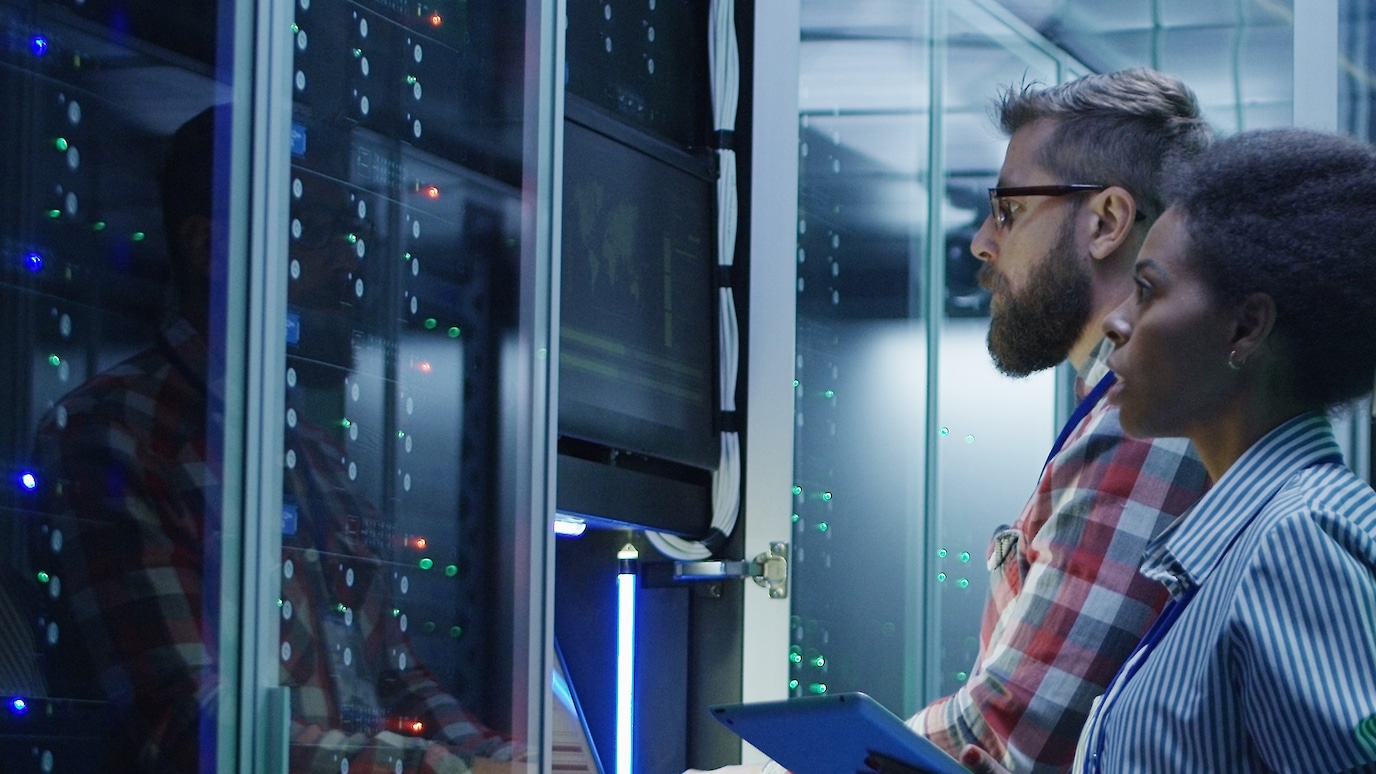 Two engineers looking at screen next to server rack