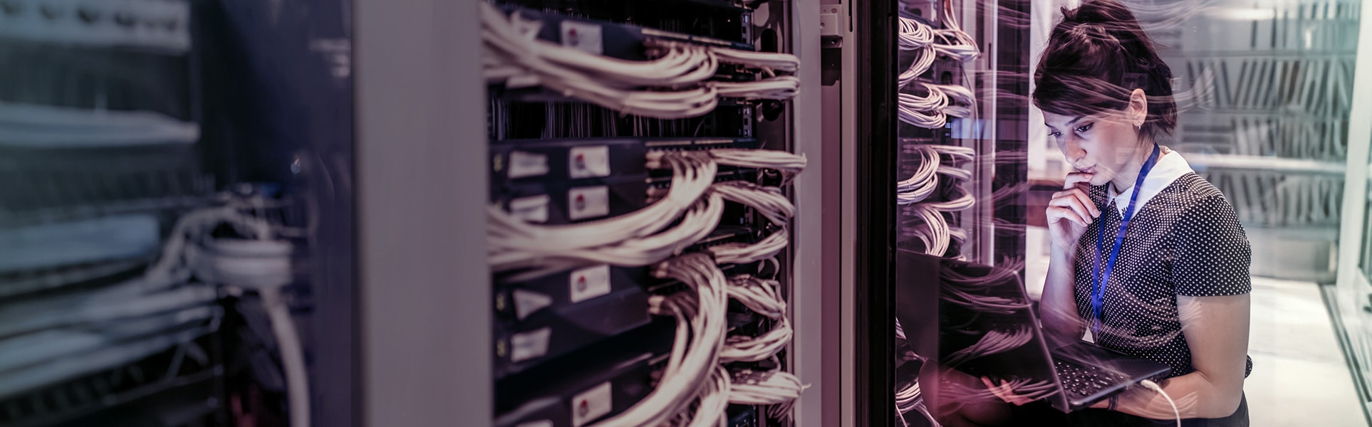 Technician studying laptop connected to server rack
