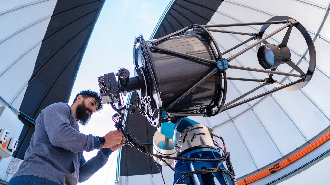 Technician adjusting high-powered telescope in an observatory