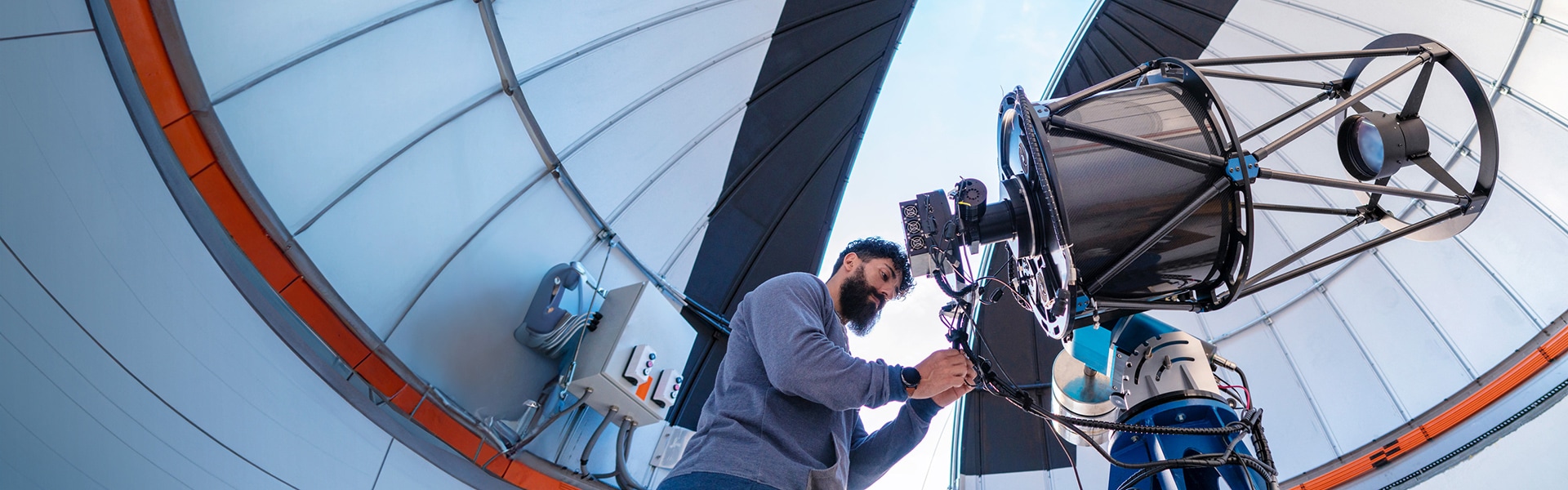 Technician adjusting high-powered telescope in an observatory