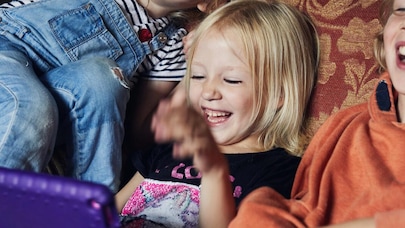Laughing children on sofa looking at tablet