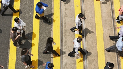 People walking over pedestrian crossing using mobile phones