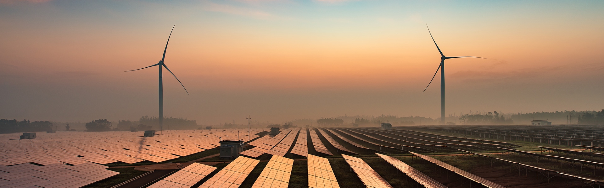 wind turbines and solar panels in field at sunset