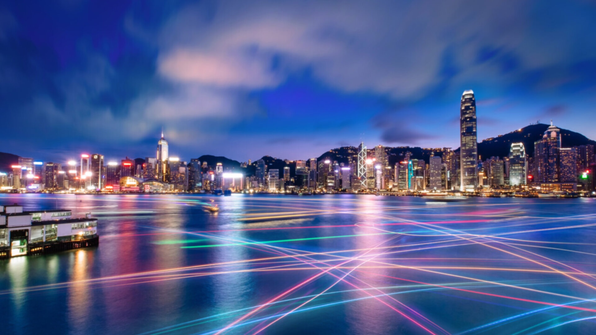 A night time view of a city skyline with colorful light trails in the water
