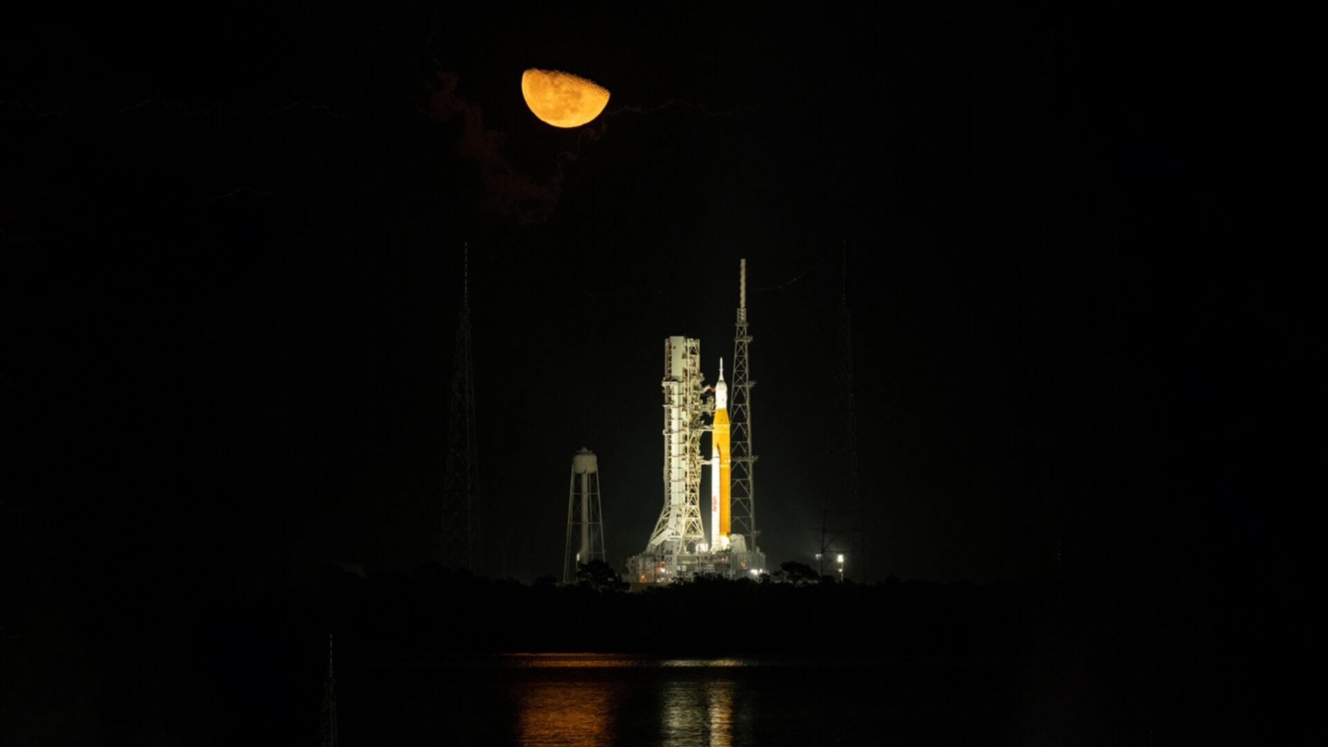 Artemis I on its launch pad, illuminated against the dark sky