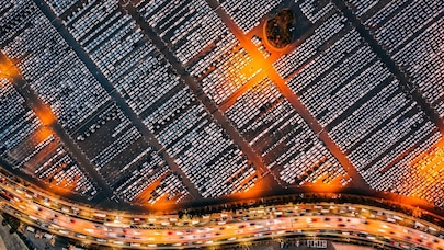 Aerial night view of car dealership next to a highway