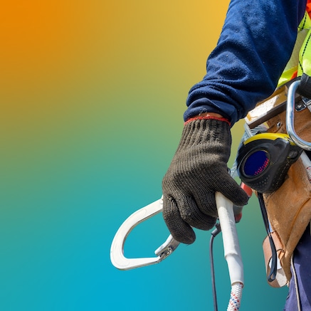 Worker in hi-viz vest holding carabiner in gloved hand