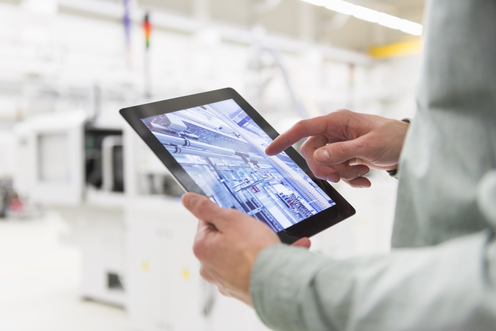 Person holding tablet device in an industrial setting