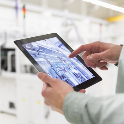 Person holding tablet device in an industrial setting