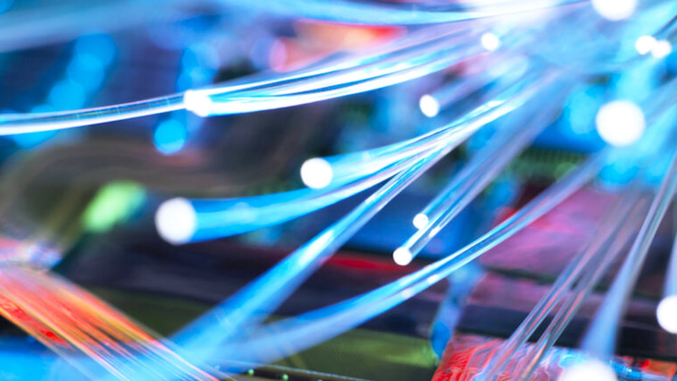 Close-up of glowing fiber optic cables transmitting data, symbolizing high-speed internet and modern network technology.