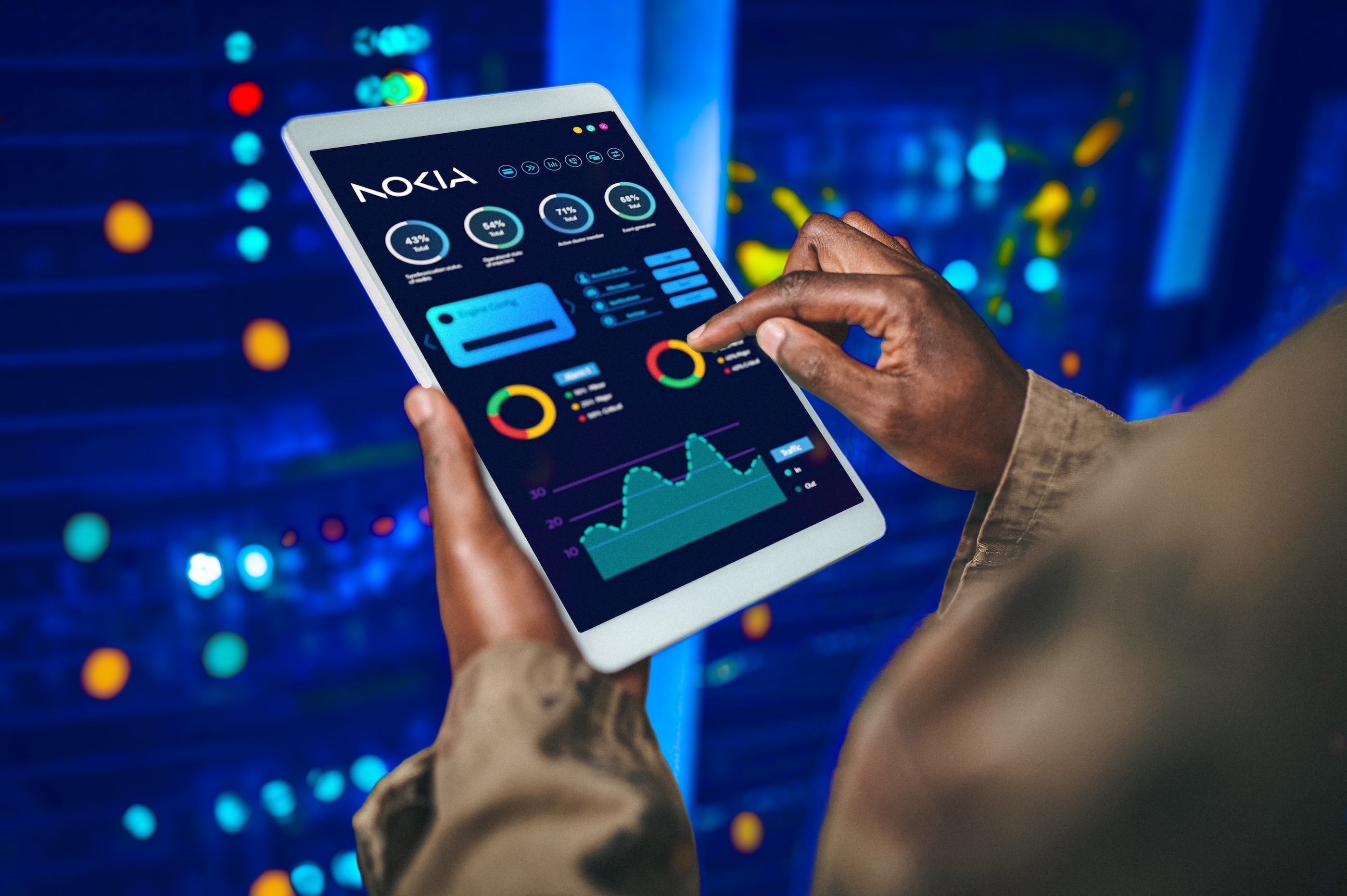 Person analyzing data on a tablet with Nokia dashboard interface, showing charts and metrics in a server room environment.
