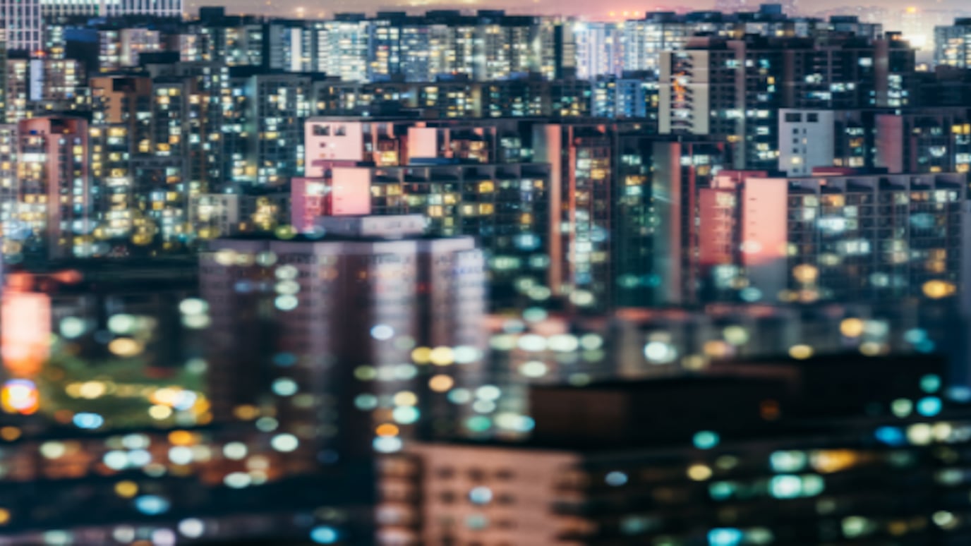 Night cityscape with high-rise apartment buildings lit by thousands of windows, creating a vibrant urban skyline.