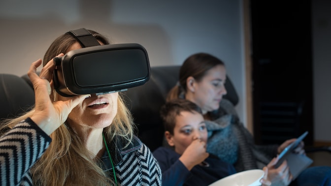 Woman wearing VR headset on sofa with her family