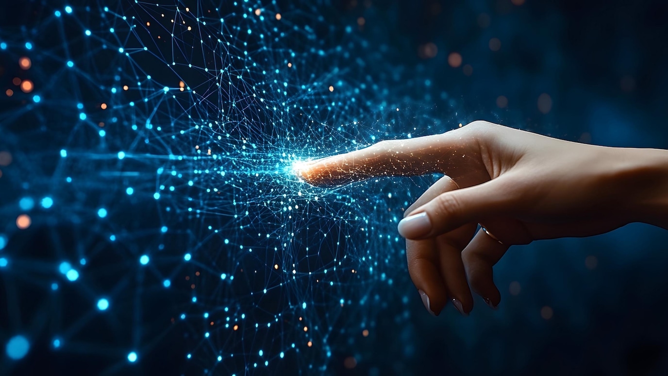Human hand touching a glowing digital network, symbolizing AI, innovation, and the connection between technology and data.