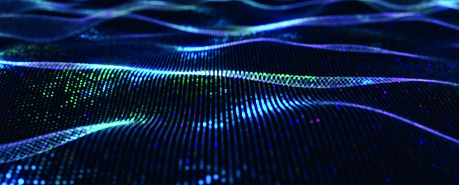 Abstract digital wave of glowing blue and green particles forming futuristic flowing lines on a dark background
