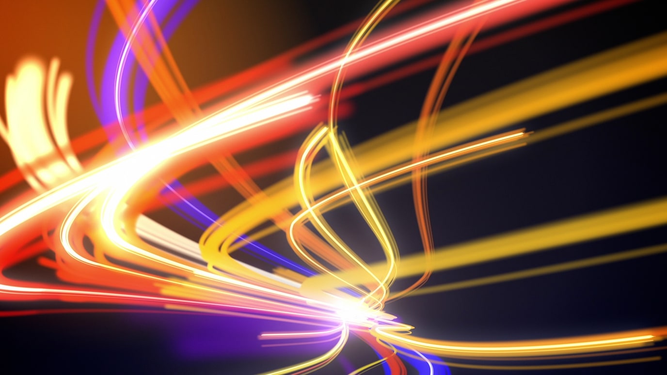 Abstract image of dynamic orange, yellow, and red light trails creating motion and energy on a dark background.