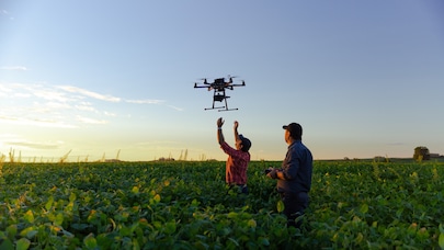 Two men control a flying drone in a field