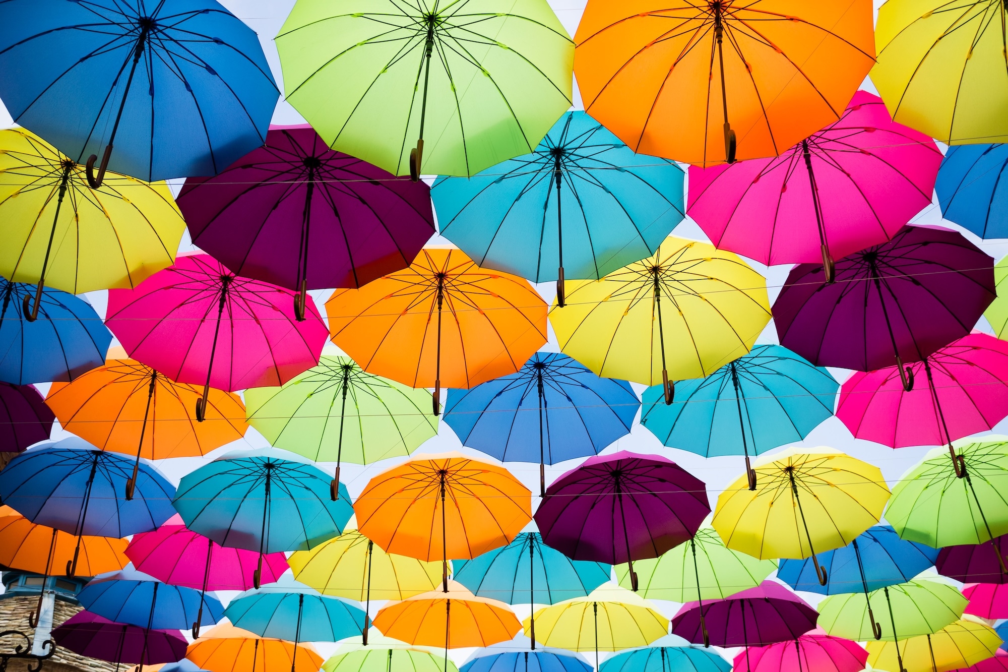 Colorful umbrellas hanging in the air as seen from below