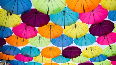 Colorful umbrellas hanging in the air as seen from below