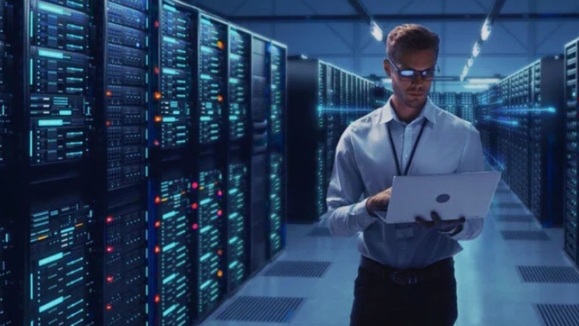 Man standing in a data-center and looking at his laptop