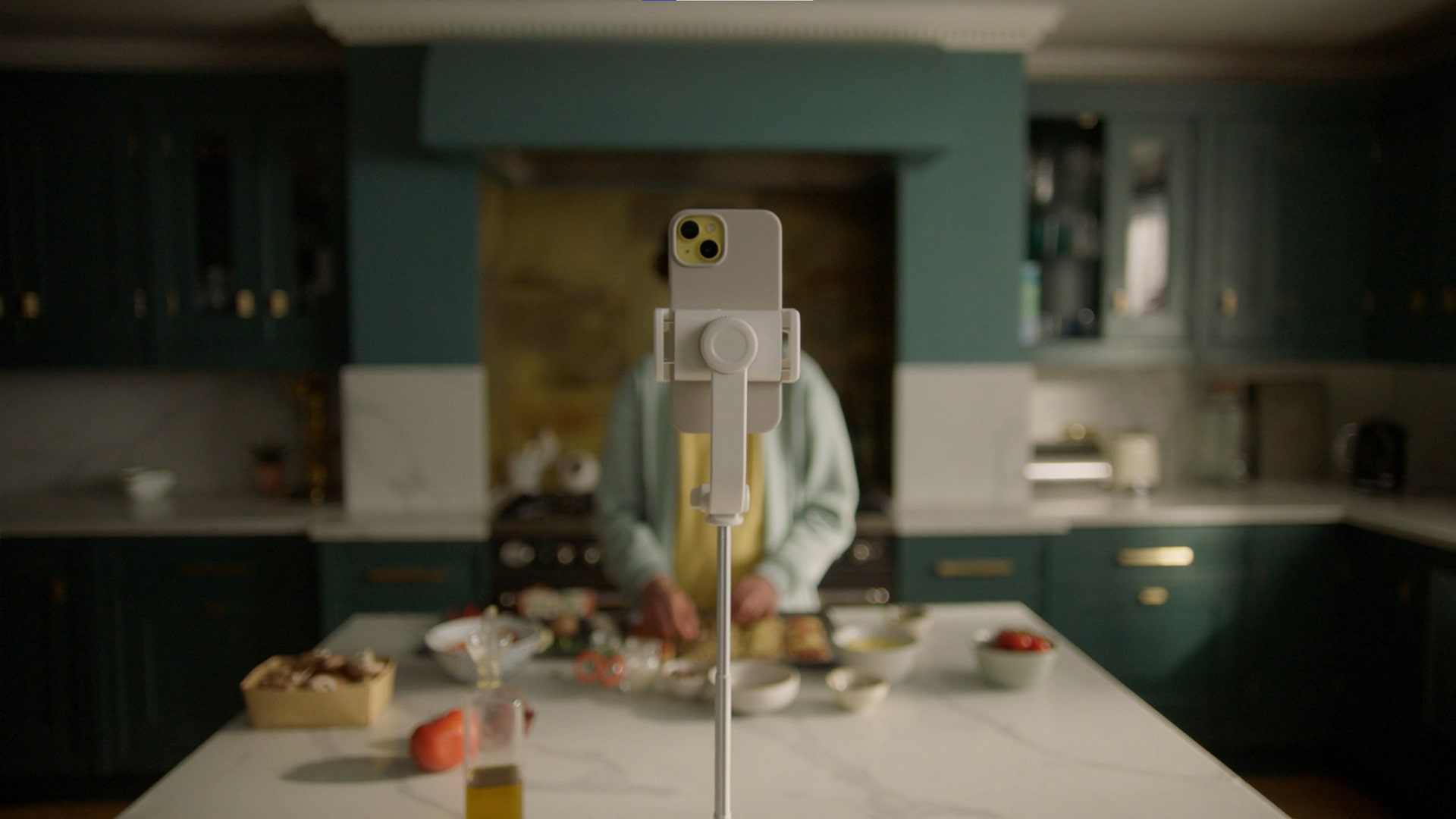 Smartphone on stand facing person preparing food on a kitchen island