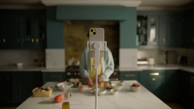 Smartphone on stand facing person preparing food on a kitchen island