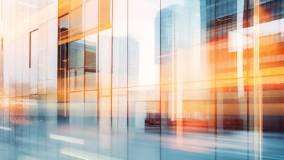 Abstract cityscape of modern glass office buildings with motion blur and warm orange light reflections