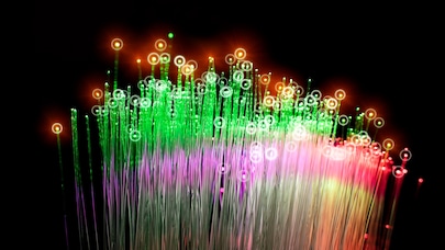 Abstract fiber optic strands glowing green, red and purple on black background, symbolizing data technology