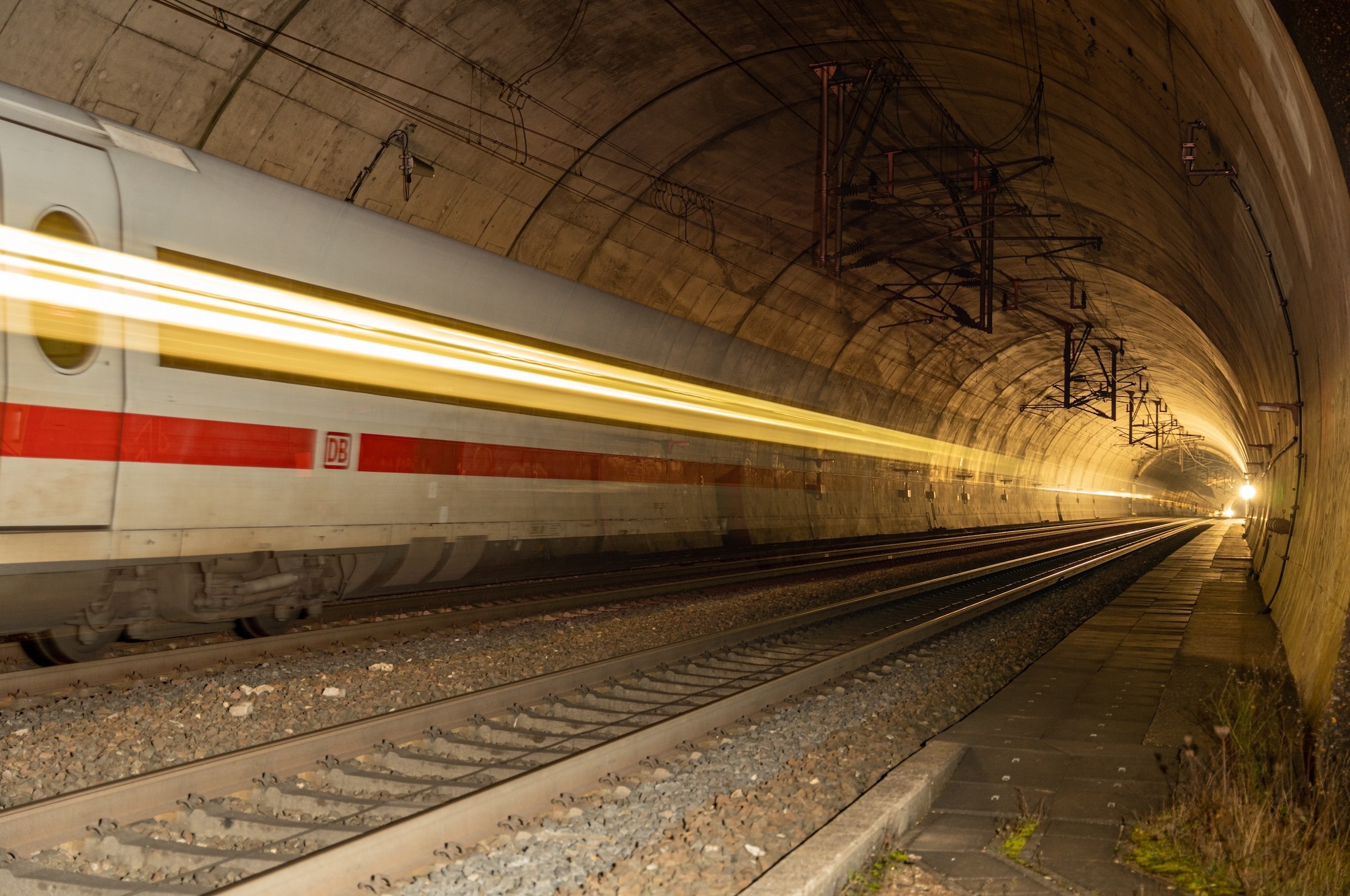 High-speed passenger train rushing through a railway tunnel with motion blur.