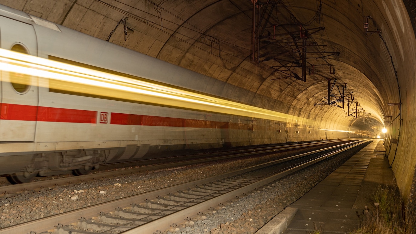 High-speed passenger train rushing through a railway tunnel with motion blur.