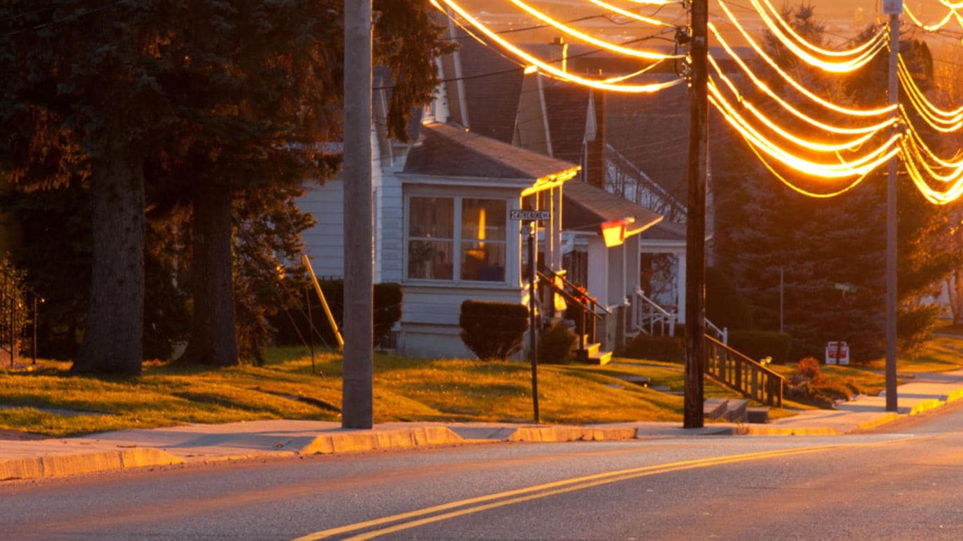 Illuminated power cables strung between poles on a residential street