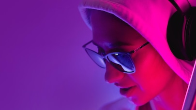 Girl wearing sunglasses and hoodie and listening to music with wireless headphones 