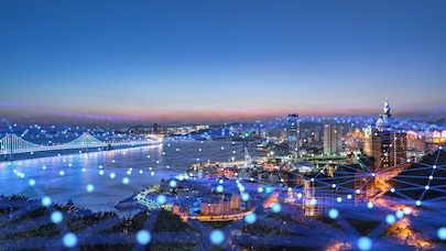 Night city skyline with illuminated bridge and waterfront, overlaid with glowing digital network connections across urban landscape