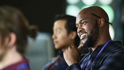 Man with pen behind ear listening in a learning session